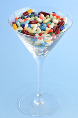 Colorful pills and tablets in cocktail glass clipart