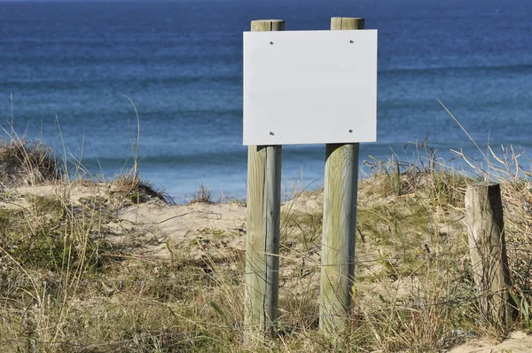 Cartelera blanca en blanco de madera en la playa de arena — Foto de Stock