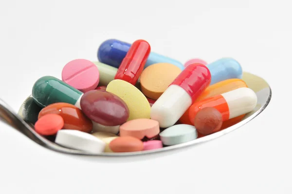 Muchas tabletas y pastillas de diferentes colores en una cuchara — Foto de Stock