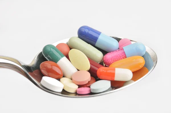 Many different colored tablets and pills on a spoon — Stock Photo, Image