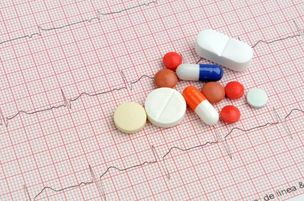 Electrocardiogram with pills and tablets above — Stock Photo, Image