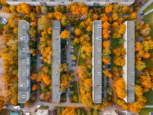 View from above on residential buildings surrounded by colorful trees. Yellow and orange foliage. Autumn season concept. Healthy living concept.