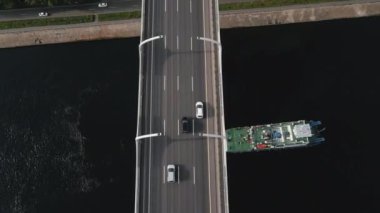 Yükseltilmiş köprüdeki çok şeritli bir yolda hava manzarası. Arabalar yüksek hızda hareket eder. Tek yönlü yol. Köprünün altındaki konut binaları. Arka planda deniz ve şehir manzarası var. Ulaşım kavramı.