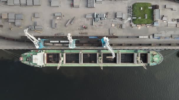 从空中俯瞰港口起重机将货物装上货舱的景象 载重货物的绿色船 轮船停泊在货运港 货物运输 — 图库视频影像
