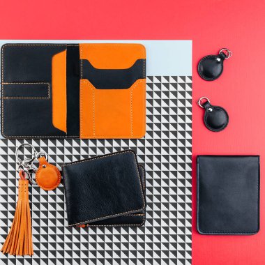 Ehliyet, pasaport ya da kimlik için siyah ve turuncu renkli deri çanta. Belgeler kapsar ve saklar. Anahtarlar için kahverengi ve siyah incik boncuklar. Düz yatıyordu. Moda aksesuar konsepti. Kırmızı arkaplan.