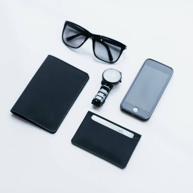 Eko derisinden alınmış şık minimalist aksesuarların düz bir fotoğrafı. Kredi kartları için ince cüzdan, pasaport ya da kimlik için tutucu, gözlükler, saatler ve cep telefonu. Moda adamı için siyah aksesuarlar. 