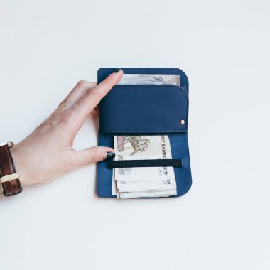 Kredi kartları ve banknotlar için mavi, ince, modern bir çanta tutuyor. Kredi kartları ve banknotlar için mavi, ince, modern bir çanta tutuyor. Ekolojik deriden yapılmış şık minimalist aksesuarlar. Düz yatar, yakın plan fotoğraf..