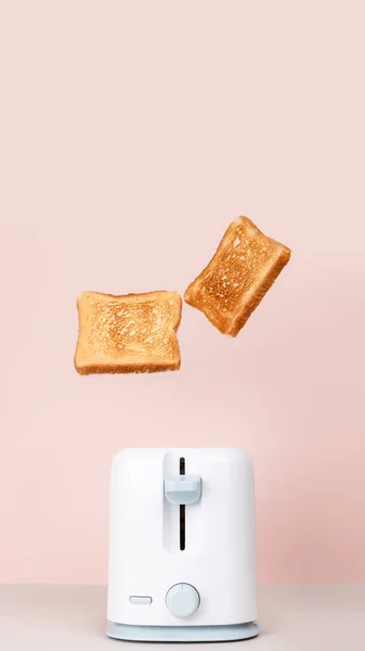 白いトースターから飛び降りるトースト 浮遊食品 新鮮な朝の食事 おいしい朝食のコンセプト ピンクの背景 コピースペース フラットレイアウト サイドビュー 縦のクローズアップ写真 — ストック写真
