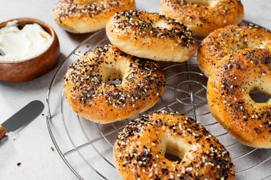 Taze pişmiş ekşi ekmek New York usulü simit açık gri masada krem peynirli.