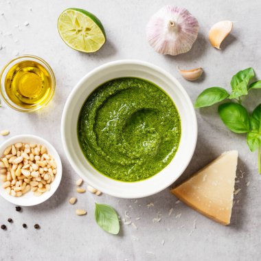 Fesleğenli taze İtalyan pesto sosu, çam fıstığı, parmesan peyniri ve açık gri arka planda zeytinyağı. Üst görünüm