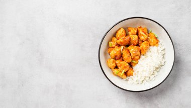 Crispy Honey Sesame Chicken garnished with basmati rice, korean style food. Light gray stone background. top view