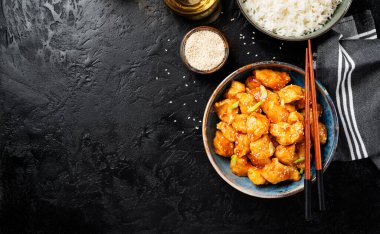 Crispy Honey Sesame Chicken, korean style food. Black stone background, top view.