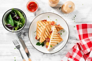 Beyaz ahşap bir masada çedar peyniri ve pastırmalı lezzetli tost sandviçler. en üstteki görünüm