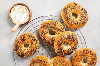Taze pişmiş ekşi ekmek New York usulü simit açık gri masada krem peynirli.