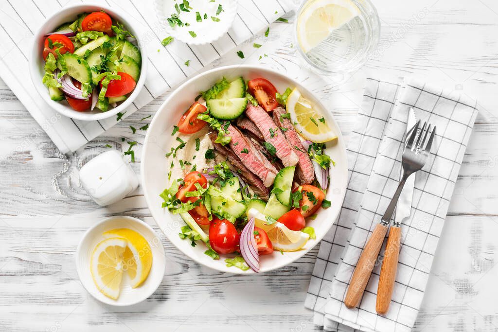 Fresh salad and creamy hummus are topped with  veggies and perfectly grilled steak in this Mediterranean Steak Bowl. top view