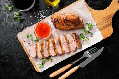 Kızarmış ördek göğsü, sos ve taze otlarla servis edilir. Siyah arkaplan, üst görünüm