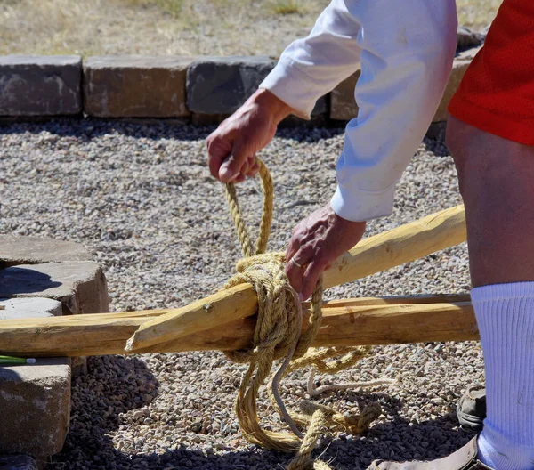 Teepee building: the main support poles are lashed together using wet rope that will dry and shrink tight.
