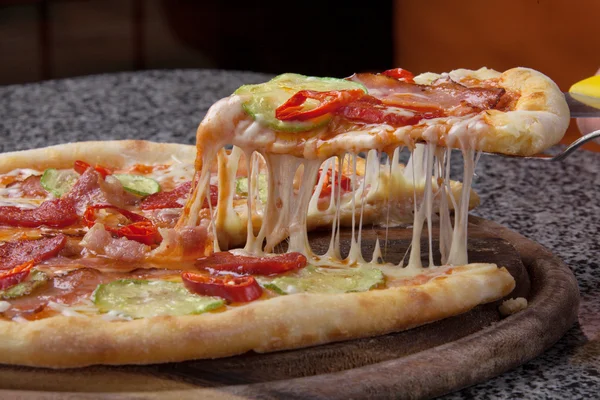 Rebanada de pizza italiana con queso derretido en un plato de madera —  Fotos de Stock