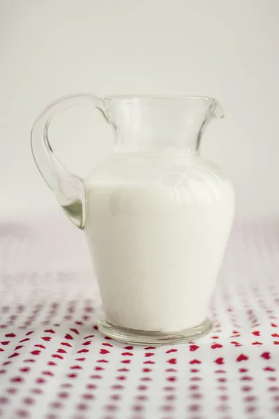 Pot de lait en verre sur une surface blanche Image En Vente