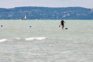 SIOFOK, HUNGARY - 30 Ağustos 2021: Genç adam, turist, kürek çekme tahtası Balaton Gölü, Siofok, Macaristan. Çeviri: