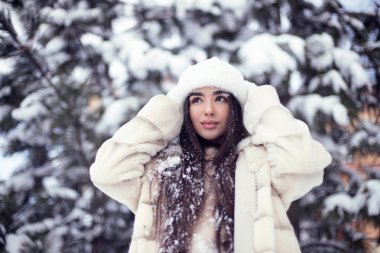 Beyaz kürklü ve beyaz şapkalı uzun saçlı güzel esmer kız otelde eğleniyor. Dış mekan fotoğrafçılığı