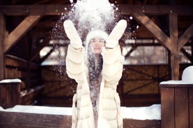 Beyaz kürklü ve beyaz şapkalı uzun saçlı güzel esmer kız otelde eğleniyor. Dış mekan fotoğrafçılığı
