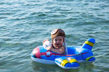 Bir çocuk, pilot kasklı bir çocuk ve şişme yüzüklü bir çocuk, denizde yüzüyor. Yüksek kalite fotoğraf