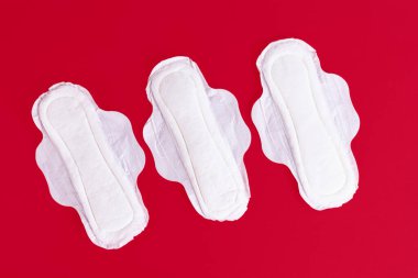 Üç tane kadın hijyenik ped, peçete. Adet dönemi boyunca kadın hijyen ürünleri. Kırmızı arka plan. Uzayı kopyala Yüksek kalite fotoğraf