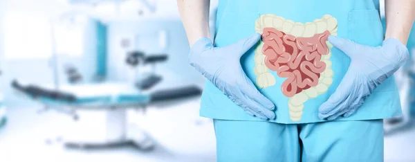 病院の手術台の背景に大腸のアイコンと制服を着た女性外科医の医師のクローズアップ 柔らかいぼやけた背景 高品質の写真 — ストック写真