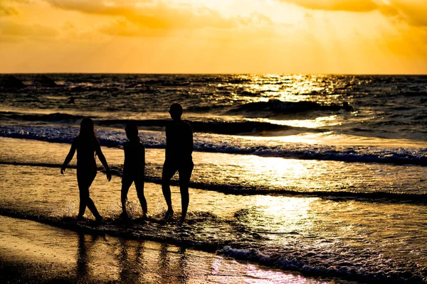 Naplemente a Földközi-tengeren. A napsugarak visszatükröződnek a vízben. Sétáló emberek sziluettjei — Stock Fotó