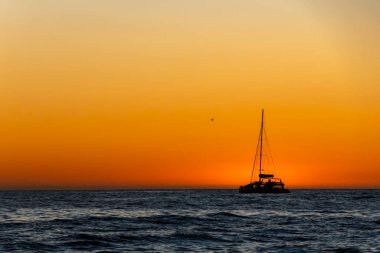 Sea yachts against the background of the sun reflected in the waves. An amazing sunset on the Atlantic Ocean.