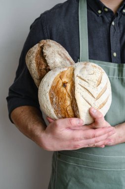 Crispy fresh bread in the hands of a man. Rustic organic wheat bread. Gluten free. Home baking bread closeup. Delicious natural foods, healthy food baking. Small business and slow food concept