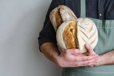 Crispy fresh bread in the hands of a man. Rustic organic wheat bread. Gluten free. Home baking bread closeup. Delicious natural foods, healthy food baking. Small business and slow food concept