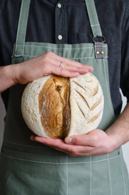 Crispy fresh bread in the hands of a man. Rustic organic wheat bread. Gluten free. Home baking bread closeup. Delicious natural foods, healthy food baking. Small business and slow food concept