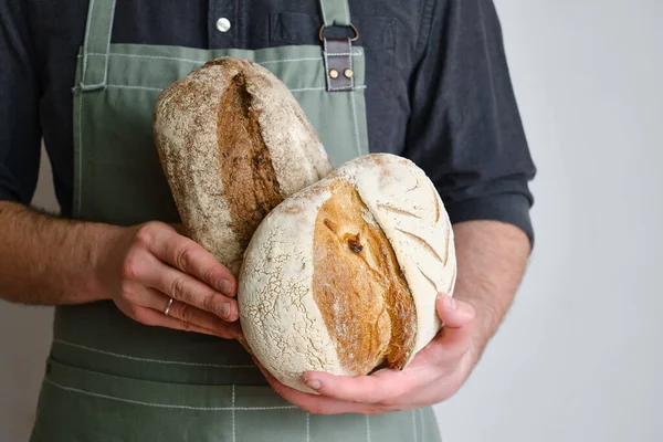 Crispy fresh bread in the hands of a man. Rustic organic wheat bread. Gluten free. Home baking bread closeup. Delicious natural foods, healthy food baking. Small business and slow food concept