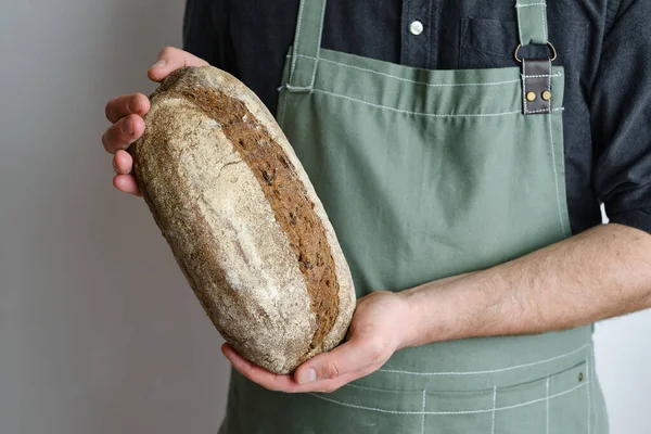 Crispy fresh bread in the hands of a man. Rustic organic wheat bread. Gluten free. Home baking bread closeup. Delicious natural foods, healthy food baking. Small business and slow food concept