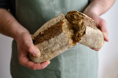 Crispy fresh bread in the hands of a man. Rustic organic wheat bread. Gluten free. Home baking bread closeup. Delicious natural foods, healthy food baking. Small business and slow food concept