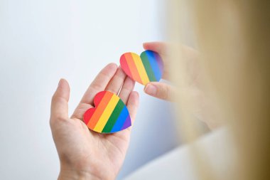 Rainbow heart from paper in woman hands in white t-shirt. LGBT flag. LGBTQIA Pride Month in June. Lesbian Gay Bisexual Transgender. Gender equality. Human rights and tolerance. Rainbow flag