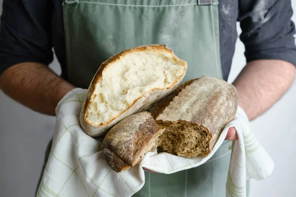 Crispy fresh bread in the hands of a man. Rustic organic wheat bread. Gluten free. Home baking bread closeup. Delicious natural foods, healthy food baking. Small business and slow food concept