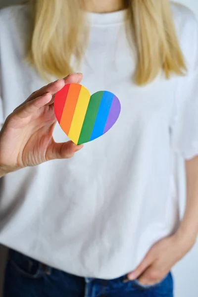 Rainbow heart from paper in woman hands in white t-shirt. LGBT flag. LGBTQIA Pride Month in June. Lesbian Gay Bisexual Transgender. Gender equality. Human rights and tolerance. Rainbow flag