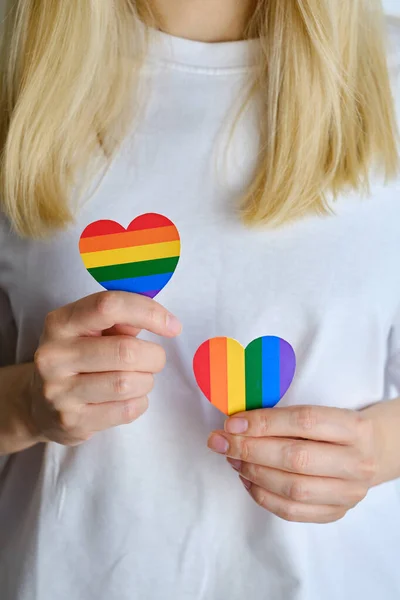 Rainbow heart from paper in woman hands in white t-shirt. LGBT flag. LGBTQIA Pride Month in June. Lesbian Gay Bisexual Transgender. Gender equality. Human rights and tolerance. Rainbow flag