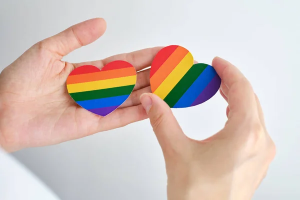 Rainbow heart from paper in woman hands in white t-shirt. LGBT flag. LGBTQIA Pride Month in June. Lesbian Gay Bisexual Transgender. Gender equality. Human rights and tolerance. Rainbow flag