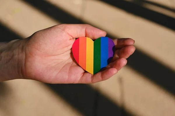 Rainbow heart from paper in woman hands. LGBT flag. LGBTQIA Pride Month in June. Lesbian Gay Bisexual Transgender. Gender equality. Human rights and tolerance. Rainbow flag