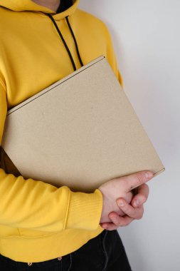 Man holds a paper box in his hand. Person with new package. Postal services, delivery. Kraft paper. Gift box, gift. Box close-up. Empty packaging, empty space. Communication of people. Cardboard case
