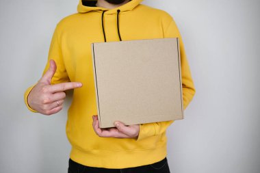 Man holds a paper box in his hand. Person with new package. Postal services, delivery. Kraft paper. Gift box, gift. Box close-up. Empty packaging, empty space. Communication of people. Cardboard case