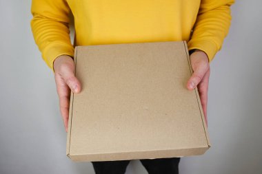 Man holds a paper box in his hand. Person with new package. Postal services, delivery. Kraft paper. Gift box, gift. Box close-up. Empty packaging, empty space. Communication of people. Cardboard case