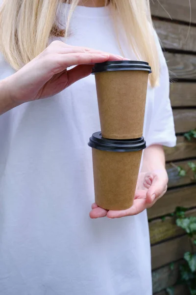 Paper cup with coffee in a woman\'s hand. Time to drink coffee in the city. Coffee to go. Enjoy the moment, take a break. Disposable paper cup close-up. Delicious hot drink. Empty space for text