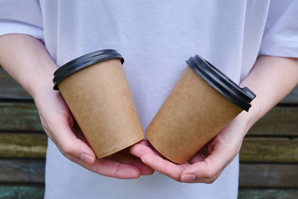 Paper cup with coffee in a woman\'s hand. Time to drink coffee in the city. Coffee to go. Enjoy the moment, take a break. Disposable paper cup close-up. Delicious hot drink. Empty space for text