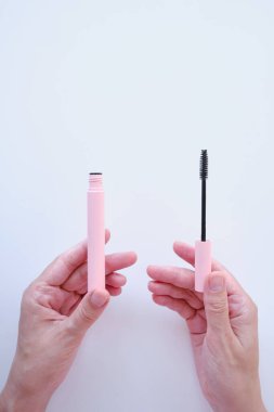 Girl hold mascara. Eyelash brush. Pink tube of mascara. Makeup cosmetics