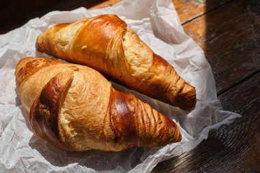 Freshly baked croissant shiny in the rays of the morning sun. Fresh homemade cakes. Delicious traditional french crispy croissants for breakfast